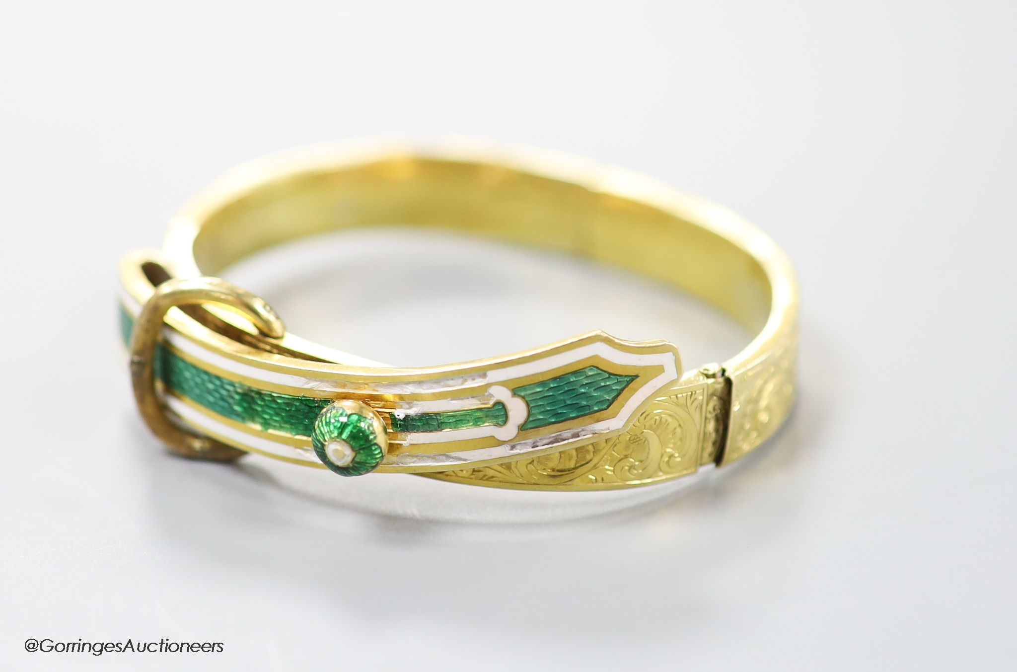 A Victorian engraved yellow metal and enamel 'buckle' hinged bracelet (a,f), gross 19.1 grams.